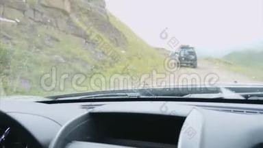在山上吉普车，从越野车的挡风玻璃上看到吉普车和岩石。